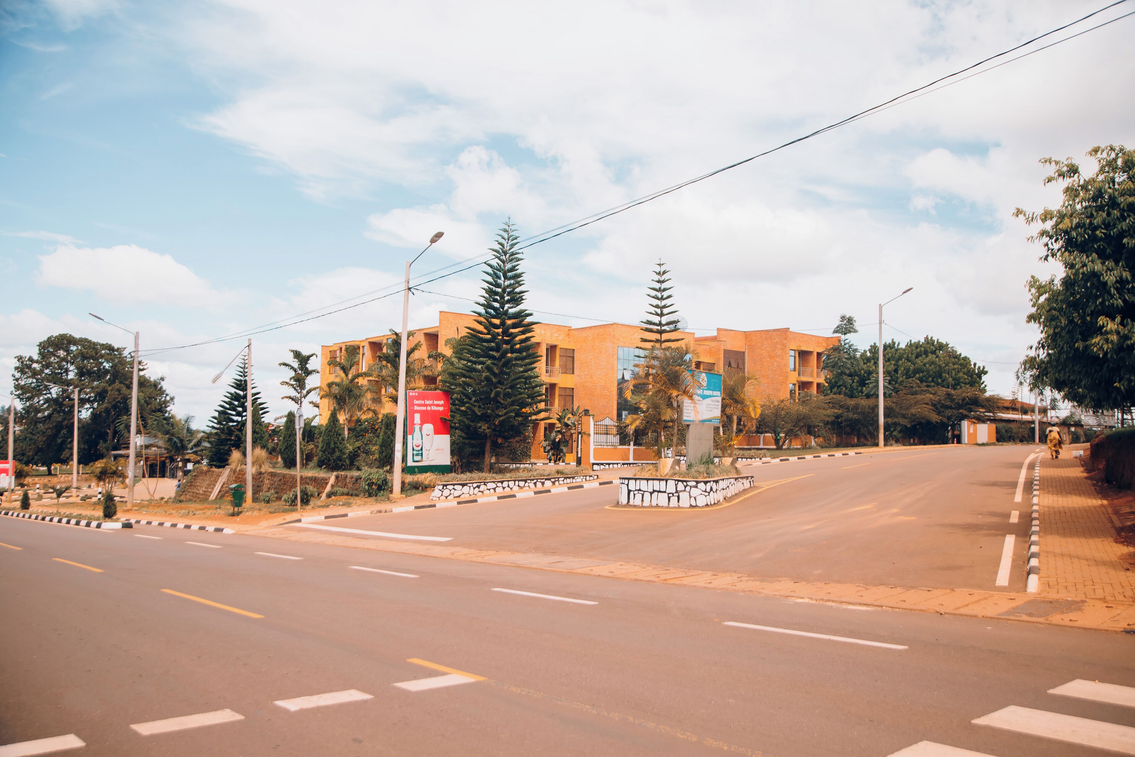 A wide road with a pedestrian crossing and a building with a modern design in the background.