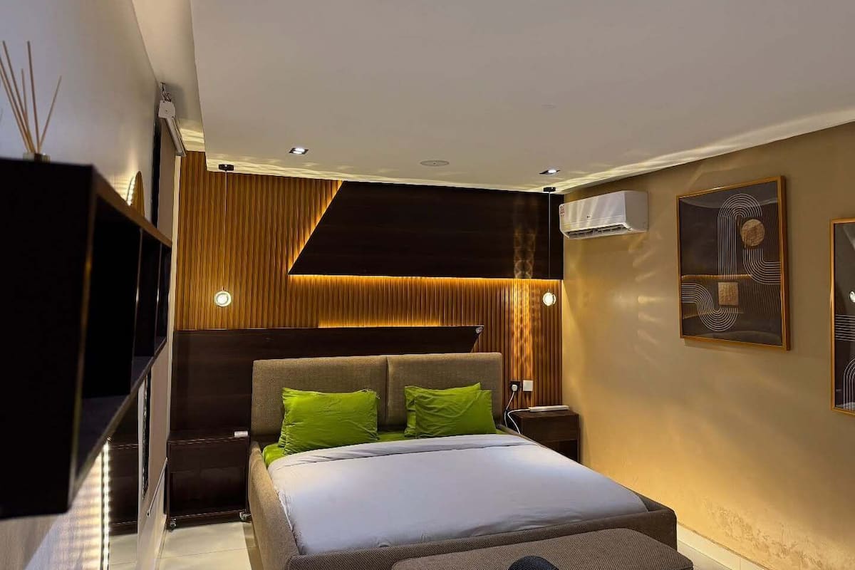 Un dormitorio moderno con cama, mesitas de noche y aire acondicionado de pared.