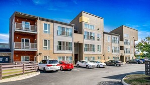 A multi-story residential building with a parking lot in front. - Updated 2-Bedroom with a pool and hot tub (Columbus)