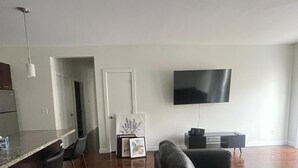 A modern living room with a large flat-screen TV, a dark leather sofa, and a minimalist design.