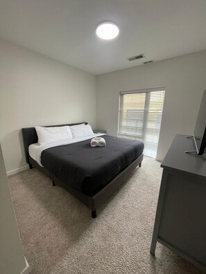 Un dormitorio con cama, escritorio y ventana con persianas.