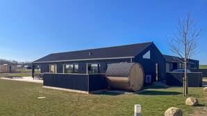 A modern building with a large cylindrical structure, a sloped roof, and a clear sky. - Gorgeous home in Børkop with sauna (Børkop)