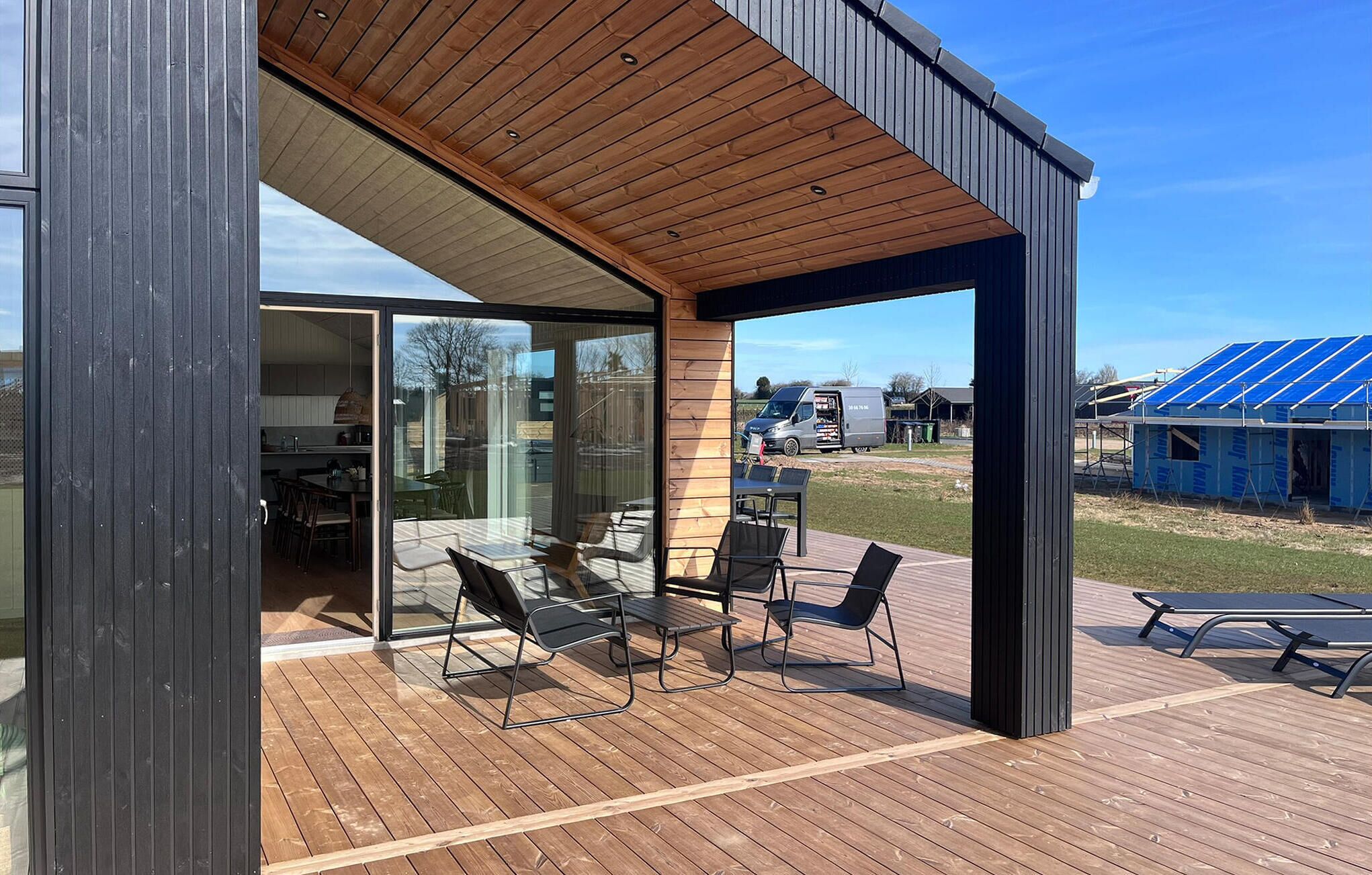 Ein modernes Haus mit Terrasse, Glastüren und freiem Blick auf den Garten.