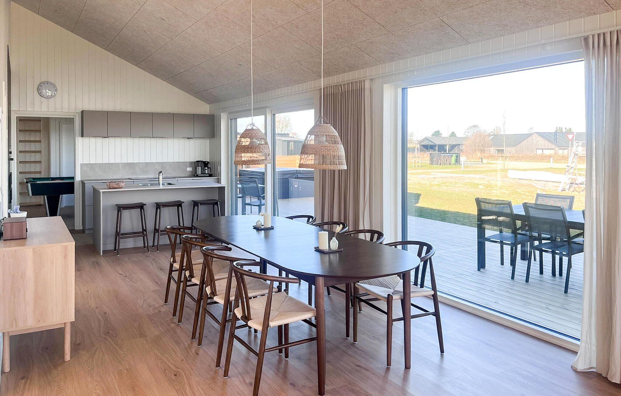 A modern kitchen with a dining area, large windows, and a view of the outdoors.