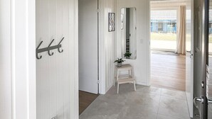 A hallway with a coat rack, a small table with a plant, a mirror, and a door leading to another room. - Gorgeous home in Børkop with sauna (Børkop)