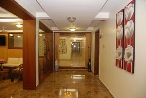 A hallway with a polished marble floor, a wooden door frame, and a wall with a floral painting.