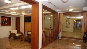 A lobby with a reception desk, wicker furniture, and decorative vases. - Hotel Rithanns (Sulur)