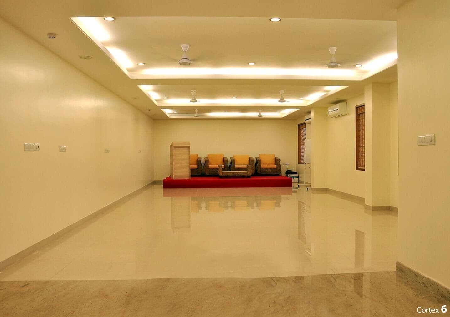 A spacious, well-lit waiting area with a red sofa and chairs, a ceiling fan, and a polished floor.