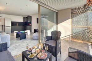 A modern living area with a dining table set with food and drinks, a kitchen in the background, and a glass partition separating the dining area from the living space. - A/C 2bdr/6P flat just two minutes from the beach! (Antibes)