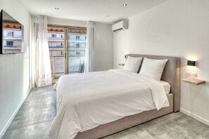 A modern bedroom with a large bed, a television on the wall, and a window with curtains. - A/C 2bdr/6P flat just two minutes from the beach! (Antibes)