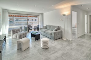 Ein modernes Wohnzimmer mit einem grauen Sofa, einem runden Hocker und einem Couchtisch.