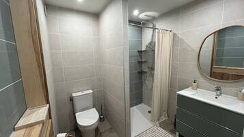 A modern bathroom with a toilet, shower, and sink.