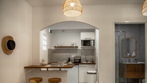 Uma cozinha moderna com uma ilha central, banquetas de madeira, micro-ondas e pia.