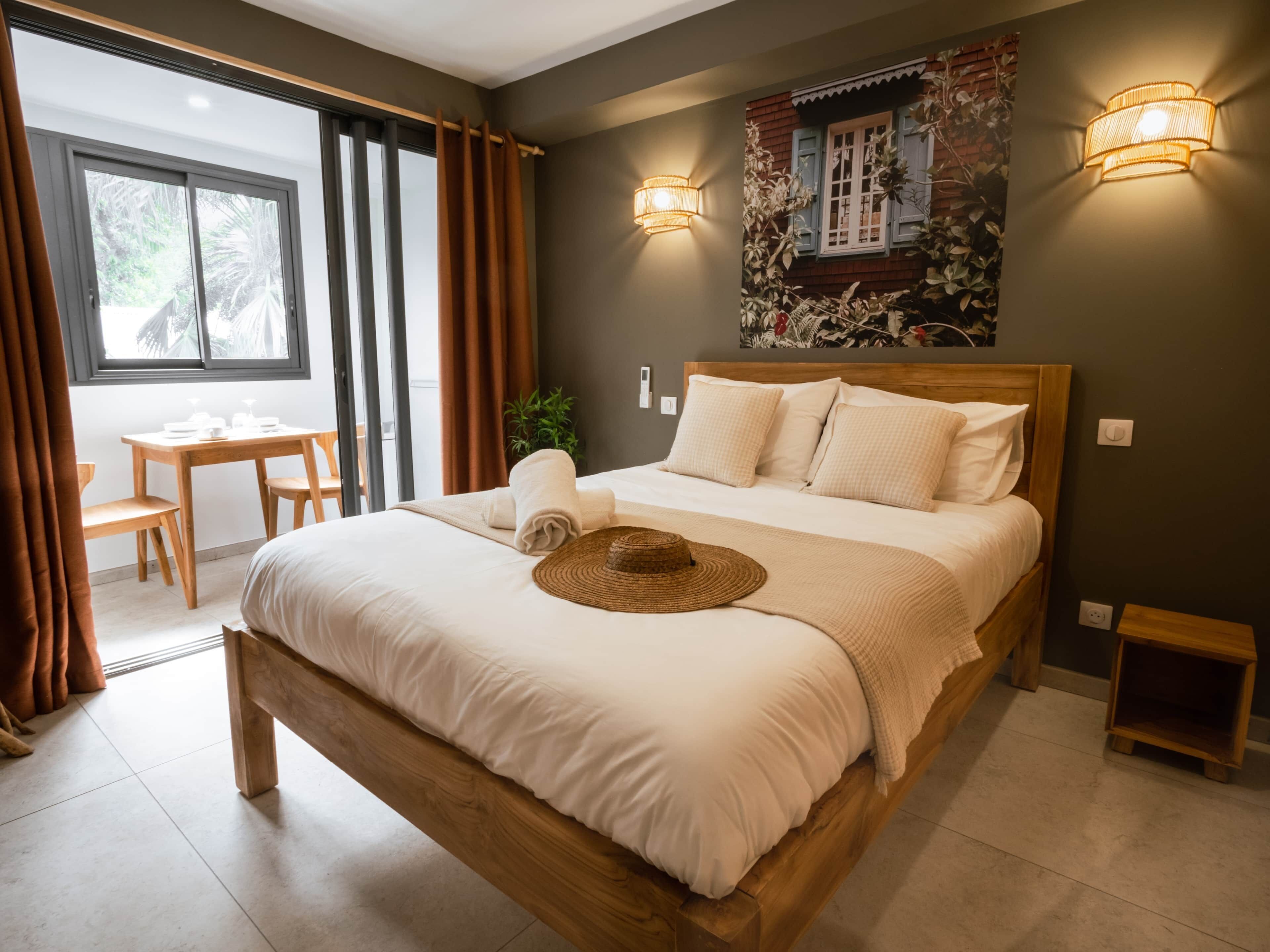 A neatly made bed with a wooden headboard, a small bedside table, and a wall-mounted light fixture.