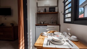 A compact kitchen with a microwave, sink, and wooden table set for dining. - Appt Endémik - L'Escale Bleue Saint-Leu, Reunion Island (Saint-Leu)