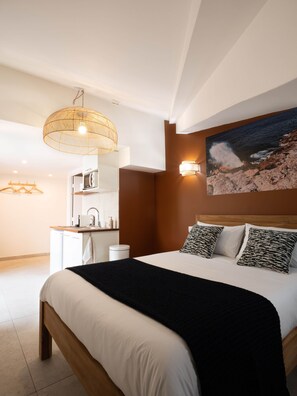 A modern bedroom with a large bed, a bedside table, a hanging light fixture, and a wall-mounted lamp. - Appt Volcanik - L'Escale Bleue Saint-Leu, Reunion Island (Saint-Leu)