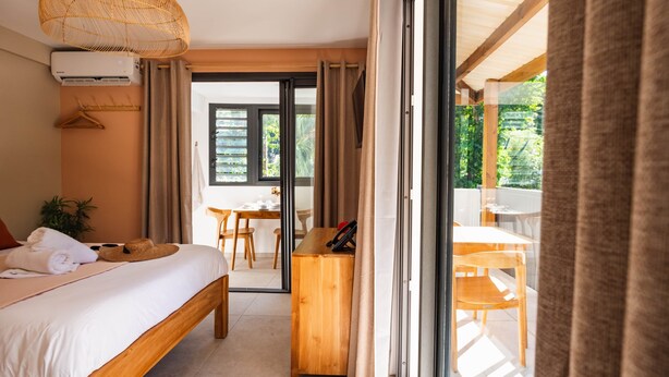 A bedroom with a bed, a desk, and a view of an outdoor area. - Appt Belle Dame - L'Escale Bleue Saint-Leu, Réunion (Saint-Leu)