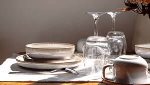A dining table set with plates, bowls, and a vase with flowers. - Appt Belle Dame - L'Escale Bleue Saint-Leu, Réunion (Saint-Leu)