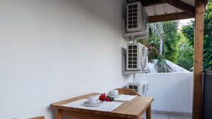 A wooden table with chairs, white cups, and a red flower on a white tablecloth. - Appt Belle Dame - L'Escale Bleue Saint-Leu, Réunion (Saint-Leu)