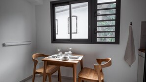 Un'angolare zona pranzo con un tavolo apparecchiato per due, una finestra con persiane e un asciugamano appeso al muro.