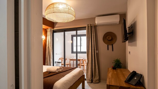 Una camera da letto con un letto, una scrivania, un telefono, una TV a parete e un condizionatore d'aria.