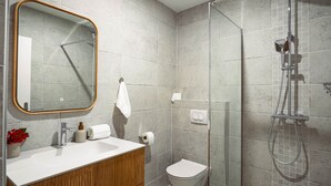 Un bagno moderno con un mobile vanitario in legno, un box doccia in vetro e uno specchio grande.