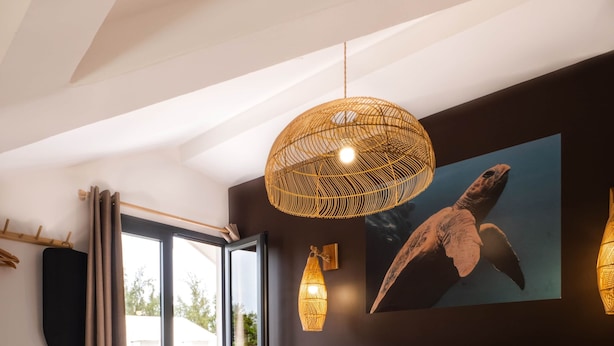 Una camera da letto con un letto grande, una testiera in legno, un quadro raffigurante una tartaruga appeso al muro e un'ampia finestra con tende.