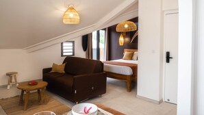 Una camera da loft accogliente con un letto grande, un angolo salotto con divano e poltrona, e un'area pranzo con tavolo in legno apparecchiato per due.