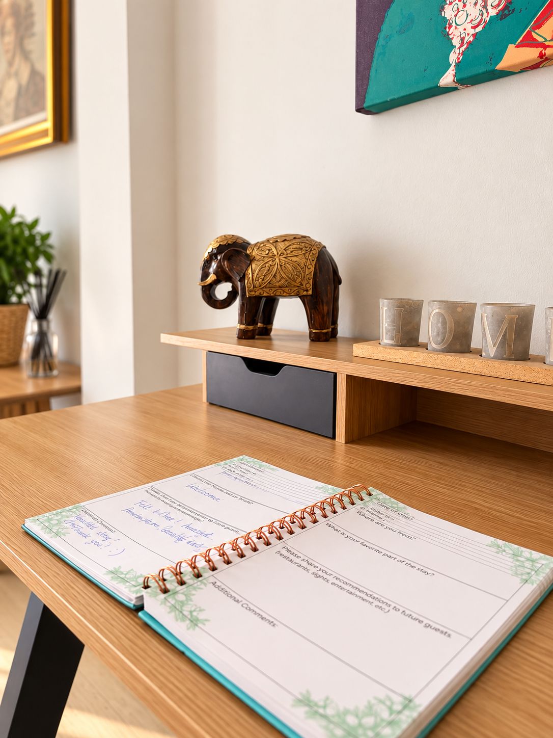 A wooden elephant figurine on a shelf, a notebook with a table layout, and a wall with a framed picture.