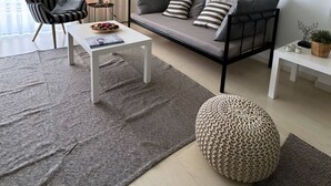 Een moderne woonkamer met een bank, fauteuil, salontafel en een schilderij aan de muur.