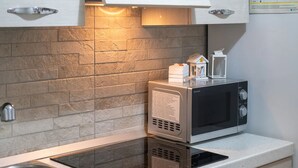 Una cocina moderna con microondas integrado, cocina vitrocerámica y pileta de acero inoxidable.