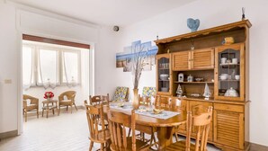 Un comedor con una mesa y sillas de madera, un aparador con puertas de cristal y un cuadro en la pared.