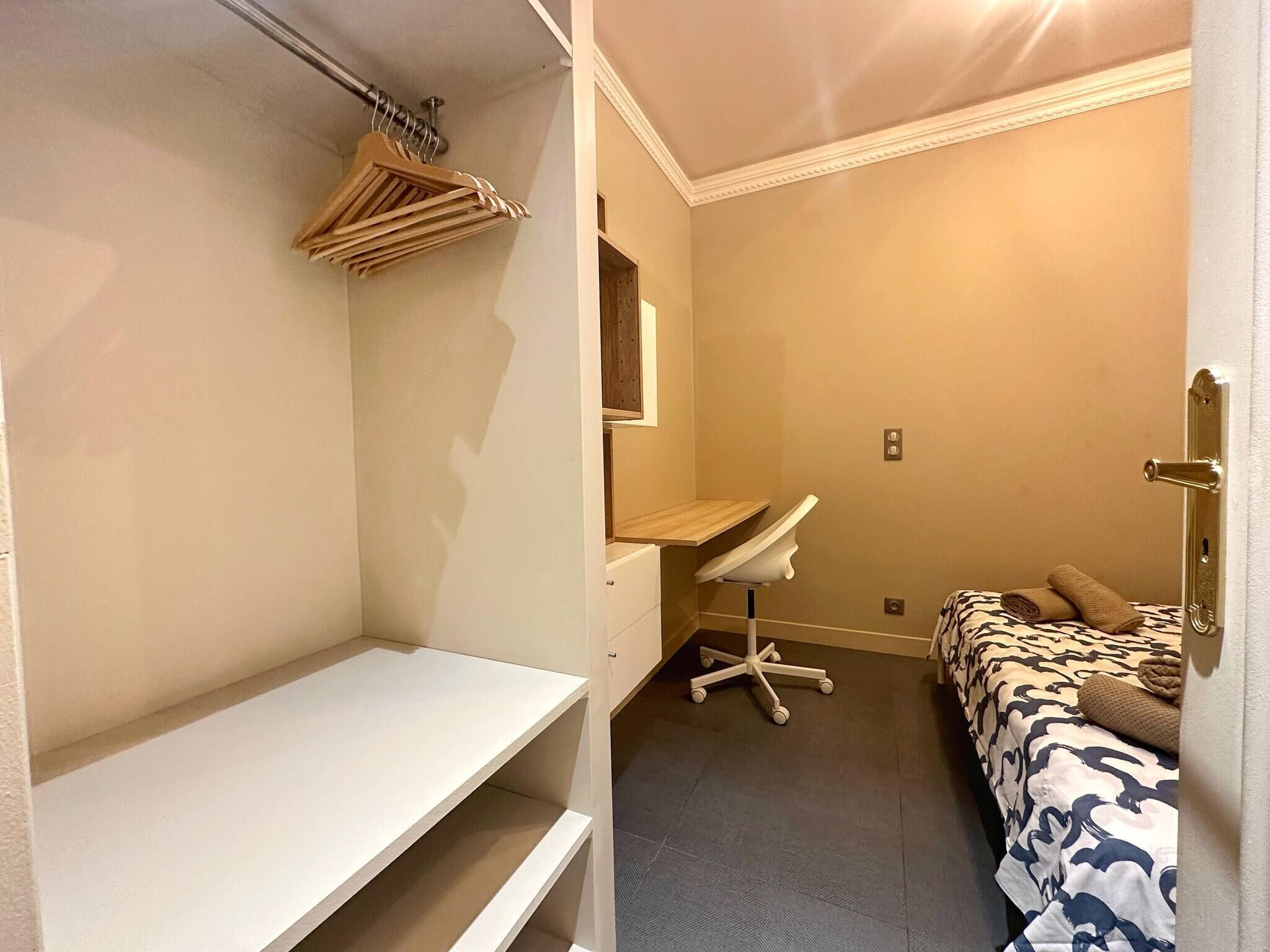 A bedroom with a bed, a desk, and a chair.