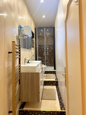 Un baño moderno con tocador, lavamanos y ducha.