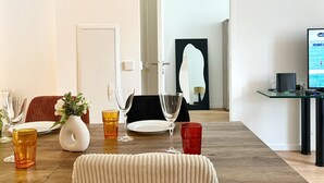 Een moderne eetruimte met een houten tafel, helder servies en een witte vaas met bloemen.