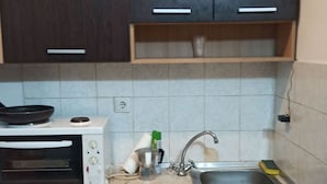 Une cuisine de taille réduite équipée d’un four à micro-ondes, d’un évier et de placards.