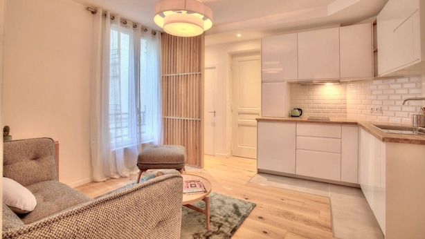 Una cocina moderna con armarios blancos, encimera de madera y una lámpara colgante.