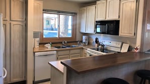 Una cocina con armarios de madera, microondas, estufa y lavavajillas.