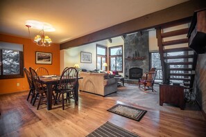 Ein geräumiges Wohnzimmer mit Kamin, Holzböden und großen Fenstern.