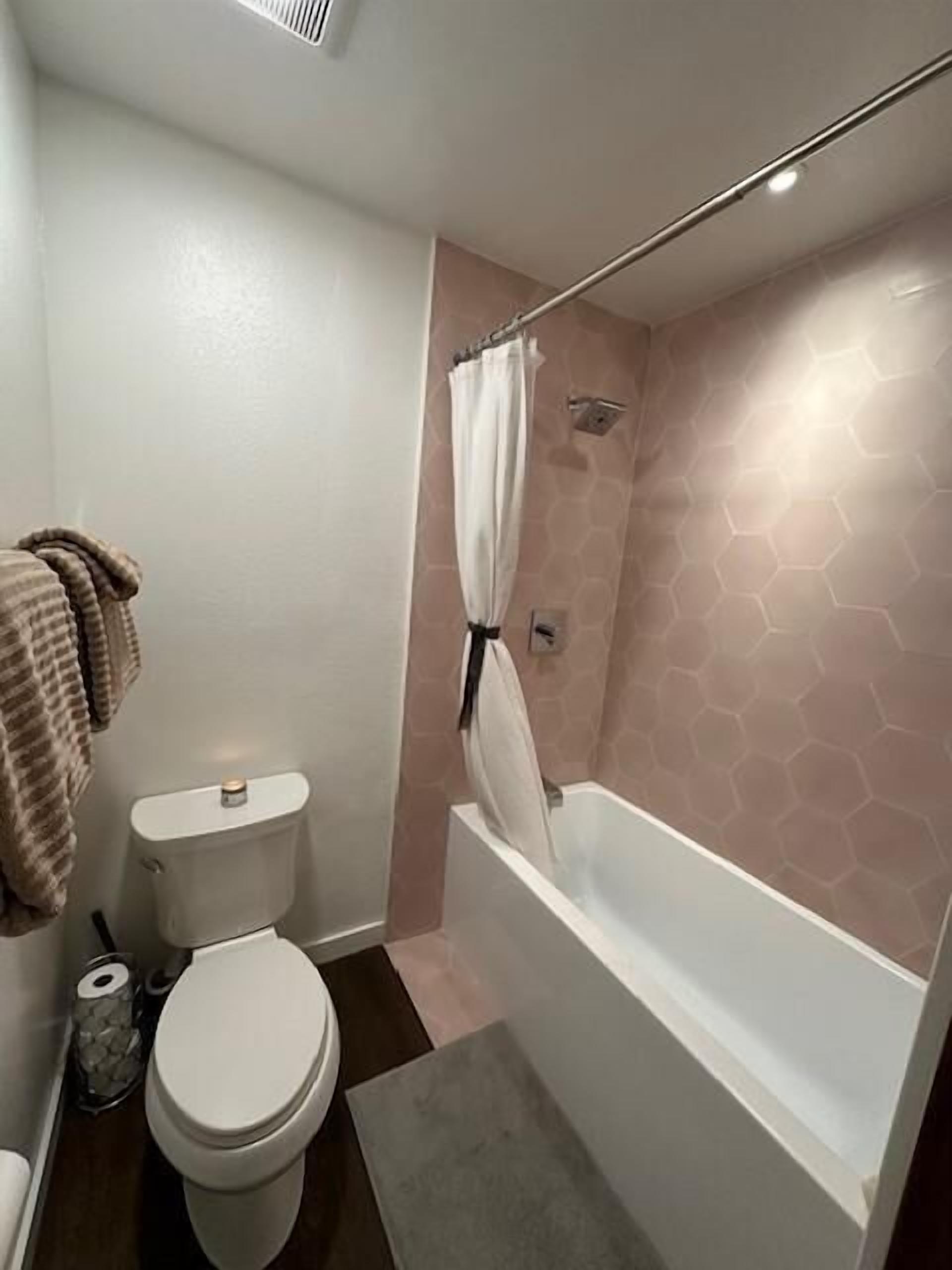 Een badkamer met toilet, douche met gordijn en bad.