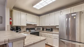 A modern kitchen with white cabinets, stainless steel appliances, and a large window above the countertop. - Mammoth Creek Unit 45 (Mammoth Lakes)