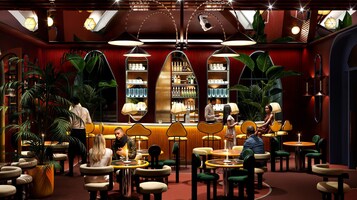 Uma área de bar com mesas e cadeiras redondas, um balcão e prateleiras com garrafas.