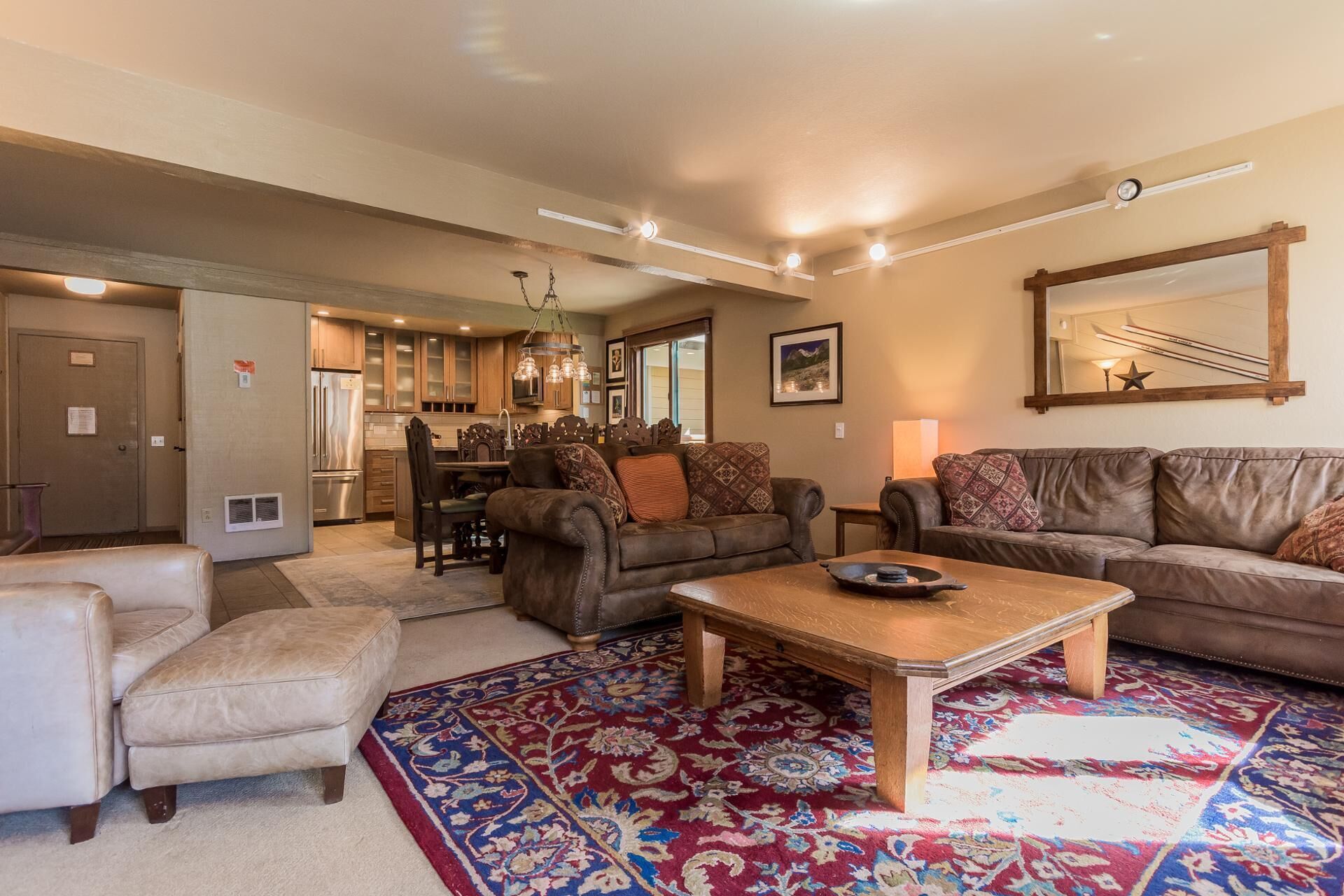 A spacious living room with a large rug, leather sofas, and a wooden coffee table.