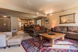 A spacious living room with a large rug, leather sofas, and a wooden coffee table. - Mammoth Creek Unit 57 (Mammoth Lakes)