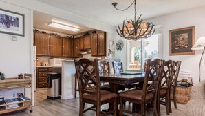 A spacious kitchen with wooden cabinets, a dining table with chairs, and a chandelier. - Mammoth Creek Unit 31 (Mammoth Lakes)