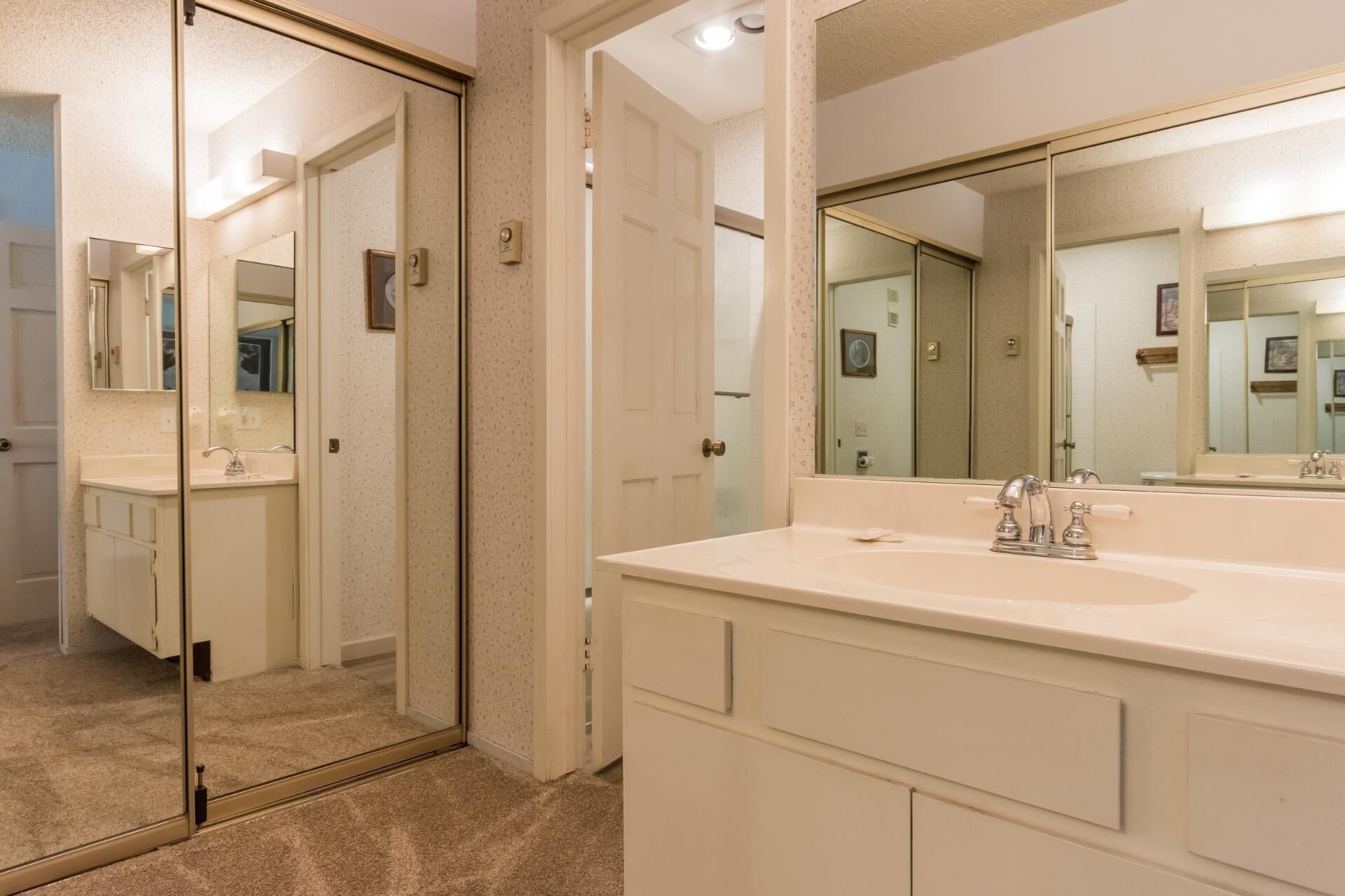 A modern bathroom with a large mirror, a double sink, and a glass shower enclosure.
