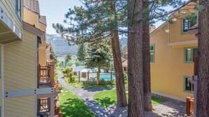 Un quartier résidentiel avec un sentier menant à une piscine, entouré d’arbres et d’immeubles dotés de balcons.