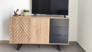 Ein modernes Unterhaltungselement mit Flachbildfernseher, Holzvertäfelung im Fischgrätmuster und einer kleinen Pflanze.