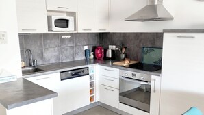 Eine moderne Küche mit weißen Schränken, einer Edelstahl-Dunstabzugshaube, einer Mikrowelle, einem Toaster und einem Spülbecken.