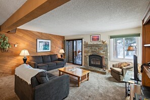 Ein gemütliches Wohnzimmer mit Kamin, einer Couch, einem Couchtisch und einem Fernseher.